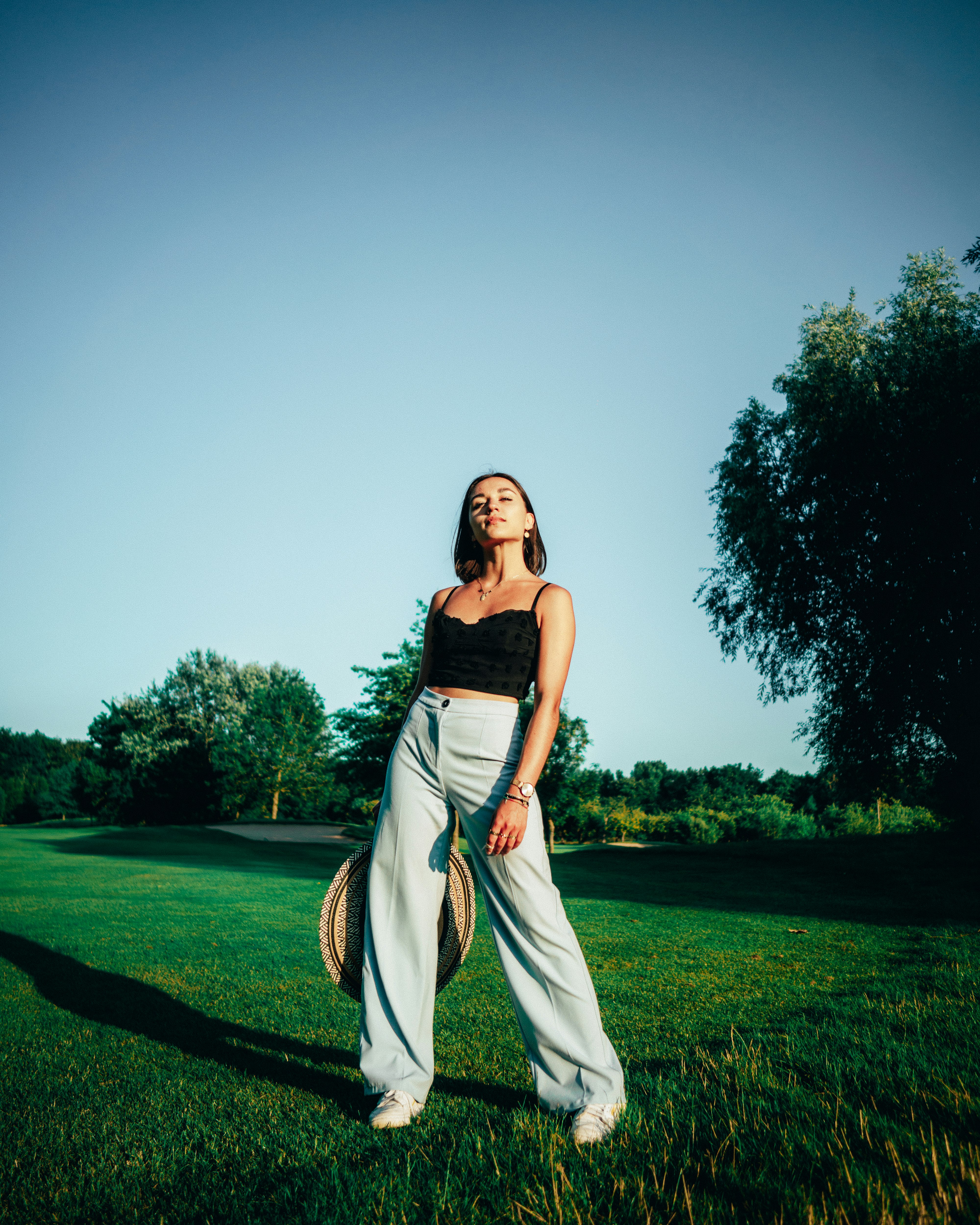 woman in black and white dress standing on green grass field under gray sky during daytime